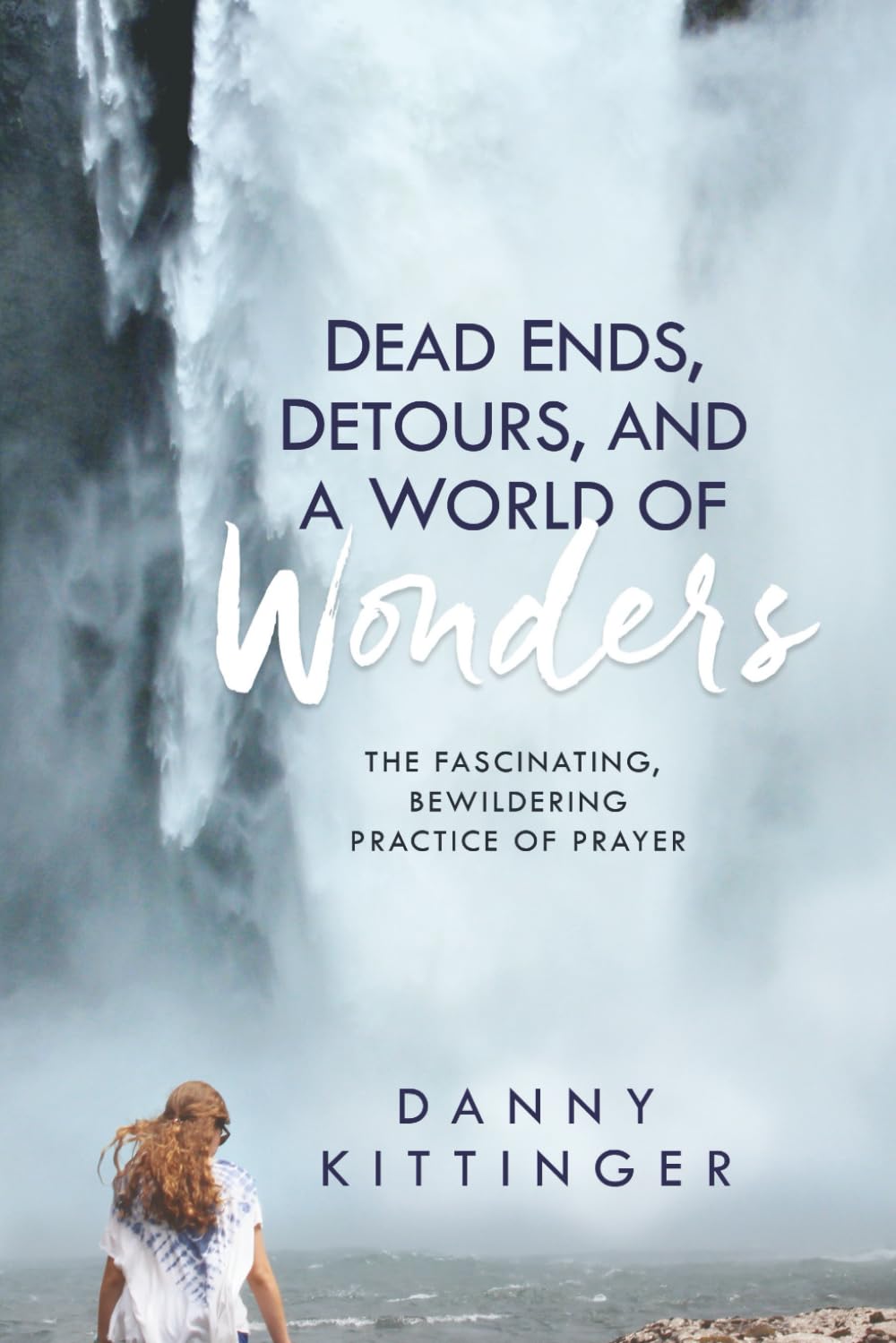 A waterfall with a young woman standing down by the pool at the base, this is the Book cover for Danny Kittinger's Dead Ends, Detours, and a World of Wonders.
